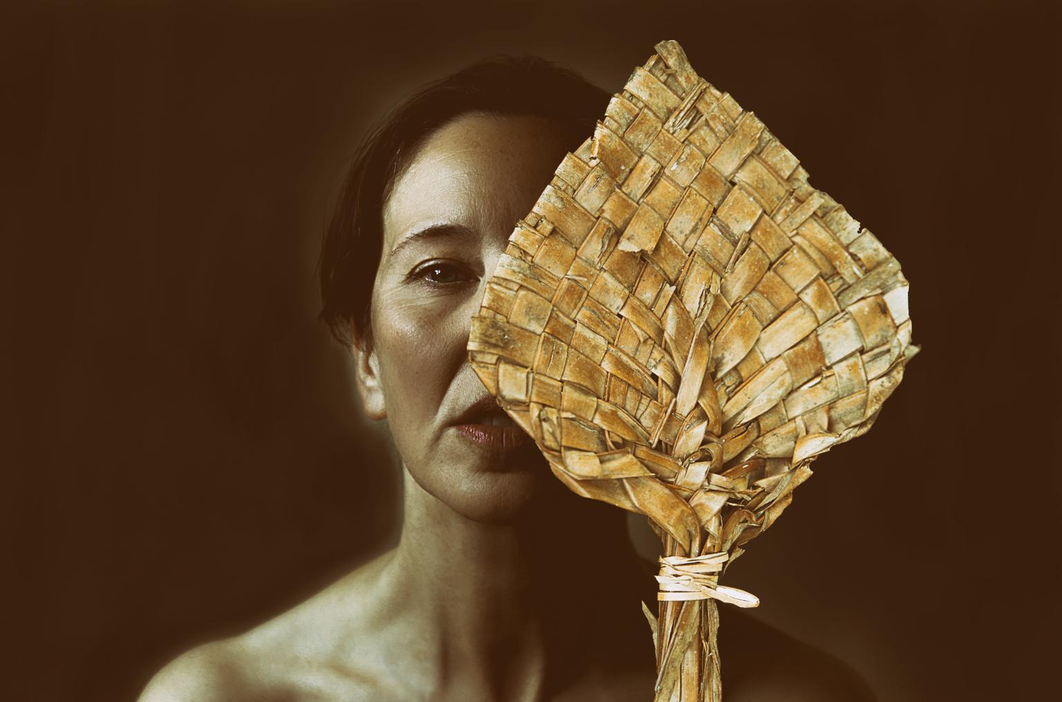Frauengesicht mit einem goldenen gewebten Blatt, das das Gesicht hab verdeckt.