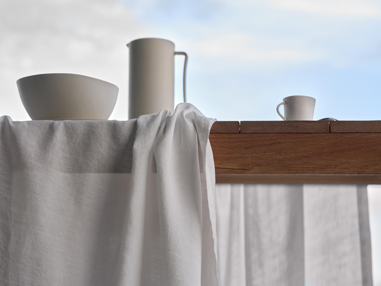 Die Kunst des Zusammenlebens bei Tisch. Der Blick fällt von unten auf einen Tisch, das Tischtuch ist verrutscht, man sieht einen Krug eine Schüssel und eine Kaffeetasse