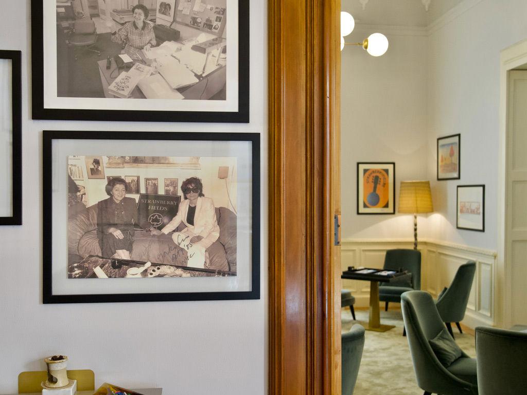 Das Bild zeigt Anne Fiermonte-Filali und Yoko Ono auf einer Couch mit dem Strawberry Fields Zeichen zwischen ihnen.