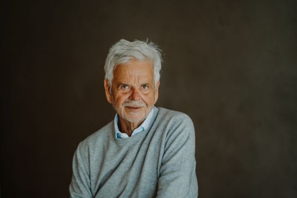 Ulrich Ladurner, founder of vigilius mountain resort and Dr. Schär, in a contemplative portrait wearing a light blue sweater against a muted background, embodying the philosophy of thoughtful hospitality and sustainable luxury