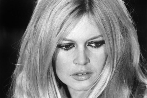 A black and white portrait of French icon Brigitte Bardot during a 1967 rehearsal at the ORTF studio in Paris. She is captured in a natural, candid moment that reflects the taste and eroticism of authenticity, wearing her signature hairstyle and an expressive look that defines her legacy of liberated fashion.
