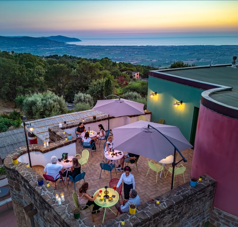 The upper terrace at Borgo La Pietraia at dusk — the plain of Paestum below, the Tyrrhenian Sea on the horizon, and the coloured architectural accents that echo the original pigments of the Greek temples. | Photo Courtesy of Borgo La Petraia