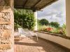 Private terrace of a suite at Borgo La Pietraia, local sandstone walls, reed pergola, white garden chairs and flowering Mediterranean garden, Cilento