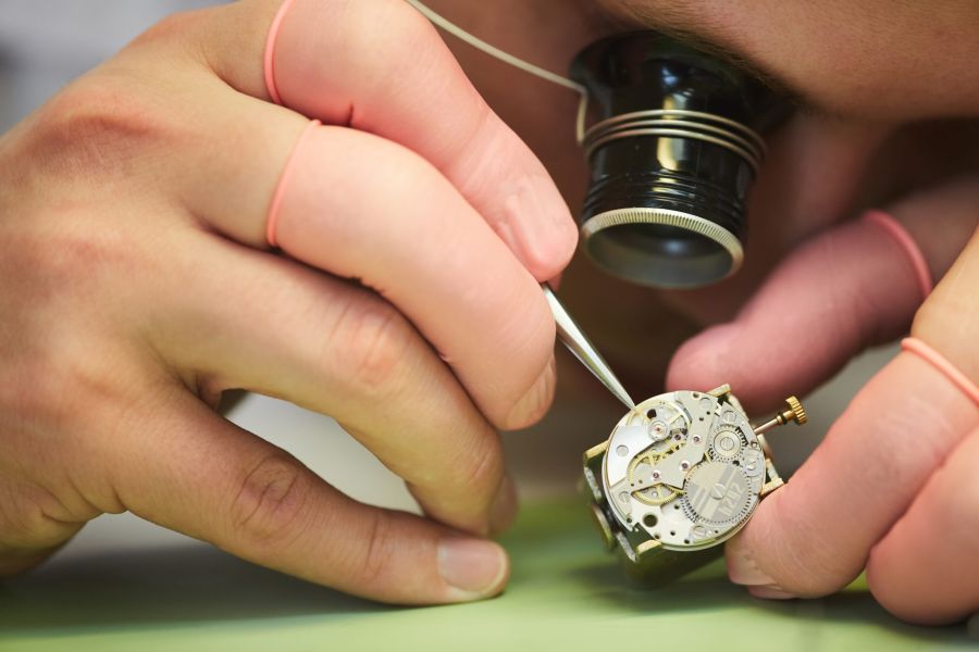 Swiss watchmaking: watchmaker adjusting a mechanical movement under magnification