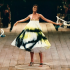 Alexander McQueen Spring/Summer 1999, collection No. 13. Shalom Harlow stands on a rotating platform as two industrial robot arms spray paint her white dress in black and yellow. Photographed by Robert Fairer. The show remains one of the most iconic moments in fashion history and a document of what Alexander McQueen stood for before the era of scalable luxury. | Photo Robert Fairer in Courtesy of Alexander McQueen