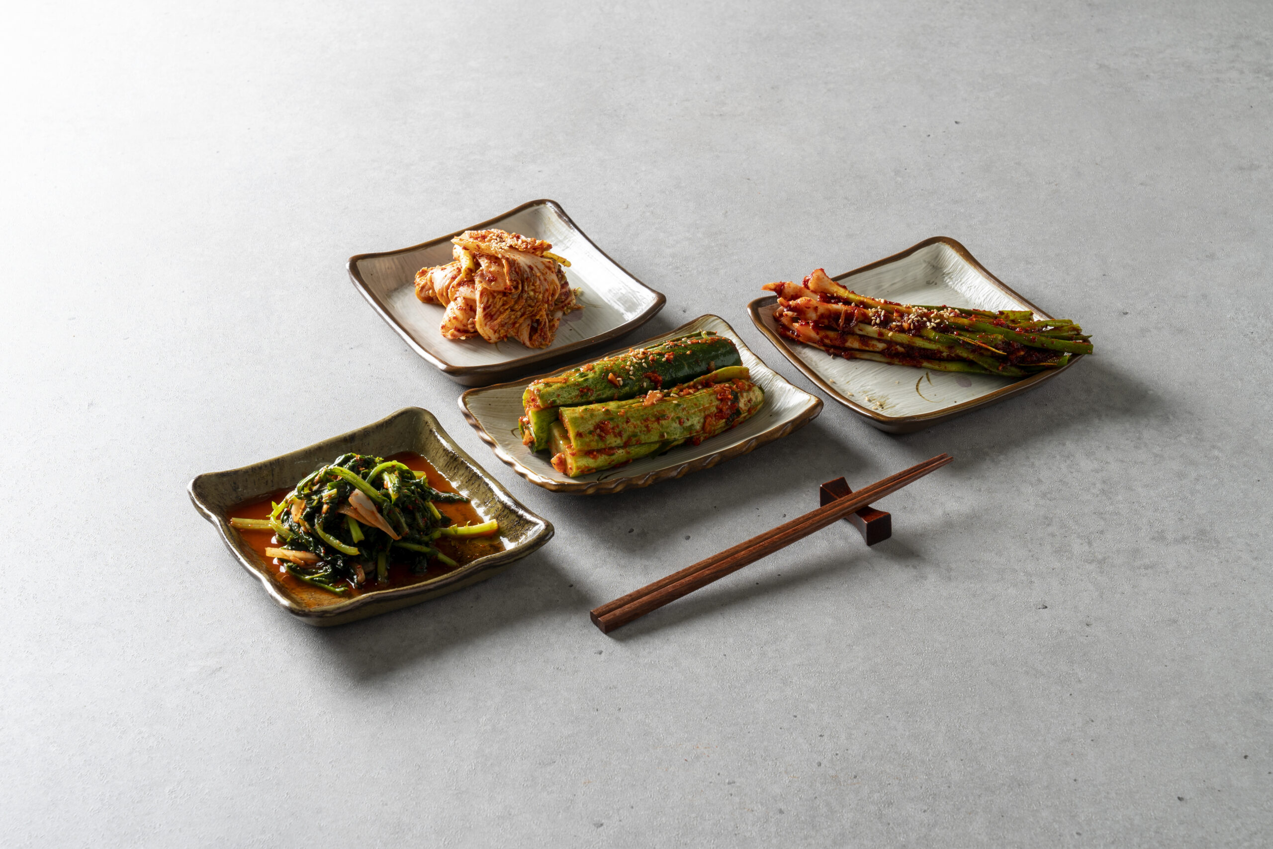 The everyday architecture of a Korean table: four kinds of kimchi, four handmade plates, one pair of chopsticks. In Busan, this is where the city begins. The Silent Luxury, June 2026. | Photo: magnific.com