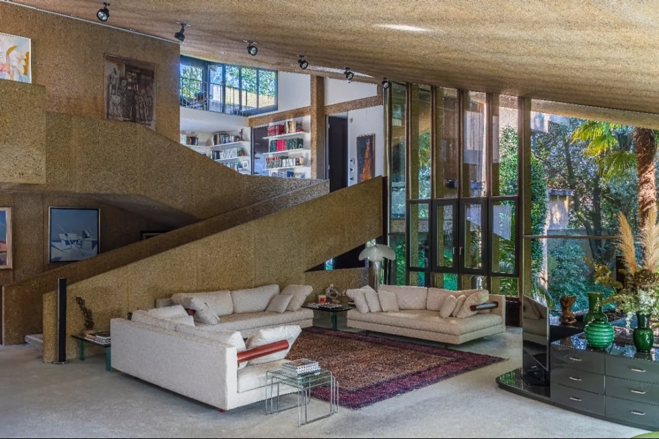 Full-height glazing under the raked concrete ceiling. The garden becomes the fourth wall of the room | Photo: Courtesy of Italy Sotheby’s International Realty