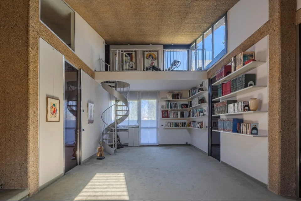 A spiral stair against white walls and exposed aggregate, in a house Castiglioni designed down to its fittings | Photo: Courtesy of Italy Sotheby’s International Realty