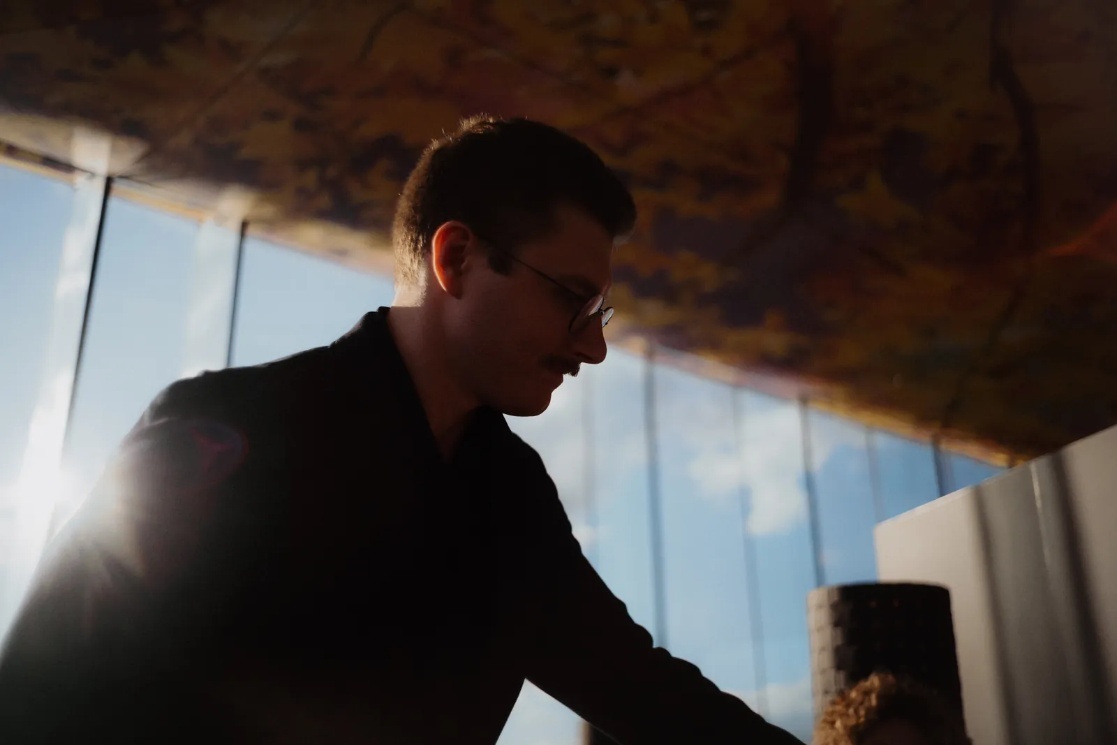 A waiter at Das LOFT in silhouette against the evening light, the illuminated ceiling above him.