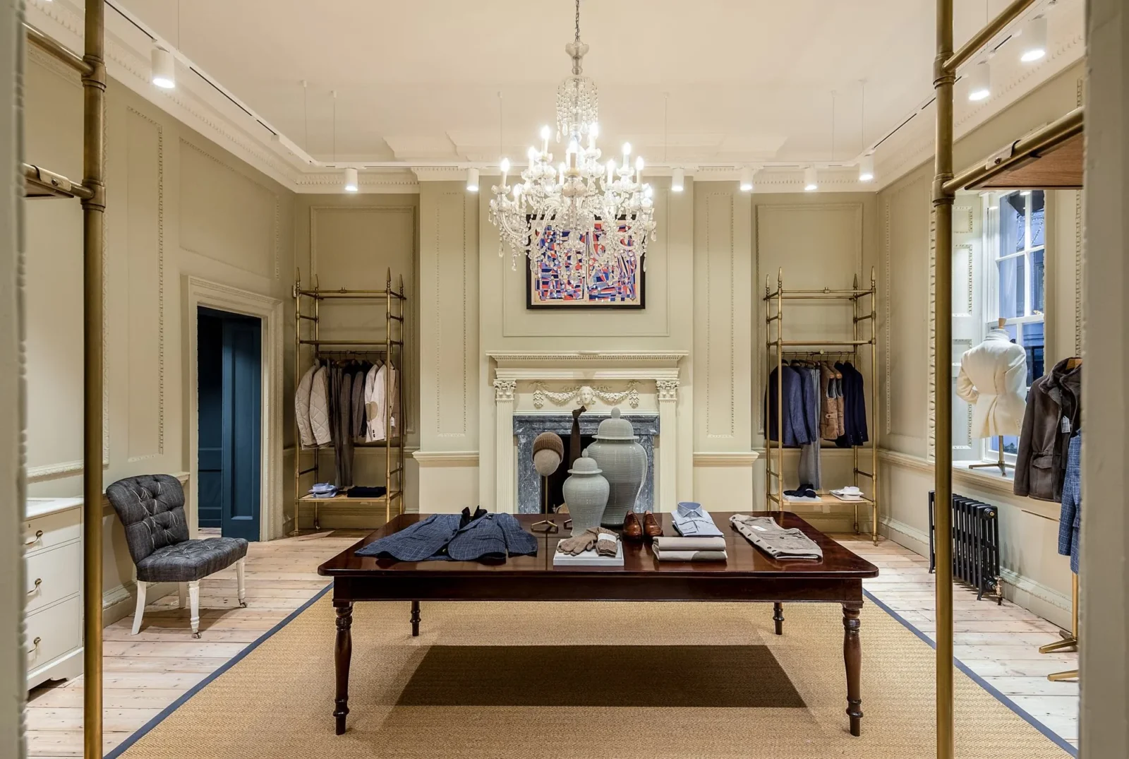 The ground floor of Hackett’s townhouse at No. 14 Savile Row, with a chandelier, a fireplace and tailoring laid out on a long table.
