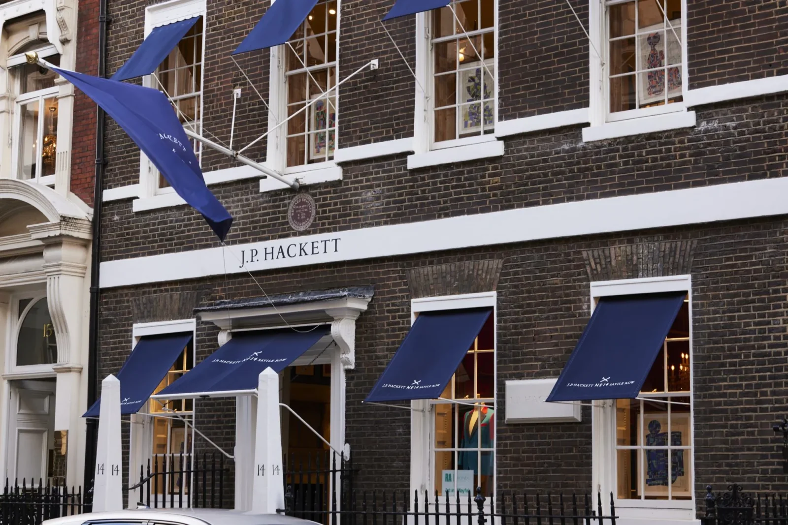 The Hackett townhouse at No. 14 Savile Row in Mayfair, London, with navy awnings and the J.P. Hackett sign above the door.
