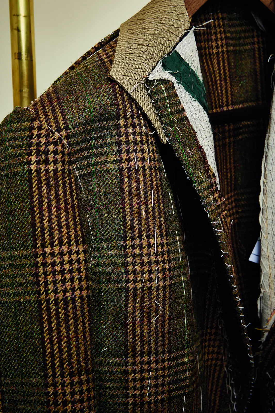 A checked Hackett tailored jacket on a stand, with a striped tie and a white shirt.