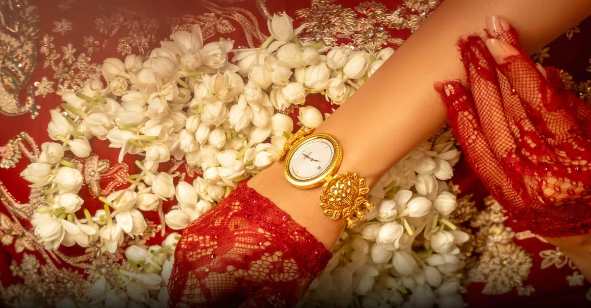 An 18-carat gold Nebula watch by Titan and Tarun Tahiliani on a bride's wrist, resting on jasmine flowers and red lace. Photo: Courtesy of Titan Company