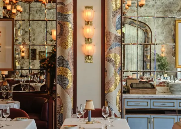 The dining room of Carbone Riviera at the Bellagio in Las Vegas, with mosaic arches, a sconce of three ribbed glass cups on a brass stem and tables laid in white. | Credit: Courtesy of Sogni di Cristallo