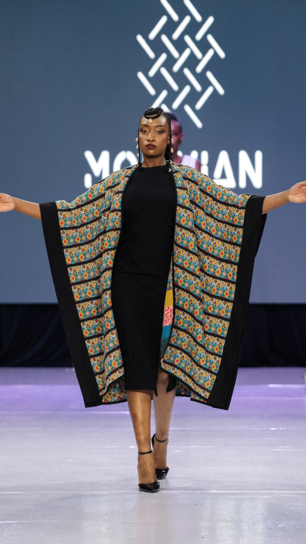 Molivian opens its Season 8 walk with a patchwork cape carrying West African geometric textile inside black tailored construction.