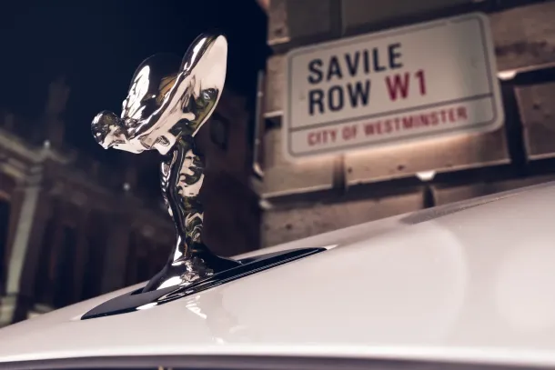 The bonnet figure of the one-of-one Ghost Savile Row in front of the street that gave the word bespoke its meaning. Bespoke designer Ieuan Hatherall built the car outward from an embroidery of 250,000 stitches beneath the rear armrest. Rolls-Royce Motor Cars | In Courtesy of Rolls-Royce