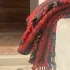 A red checked wool blanket with tufted, fringed edges lies folded over a stone wall in the courtyard of Lanificio Bottoli in Vittorio Veneto.