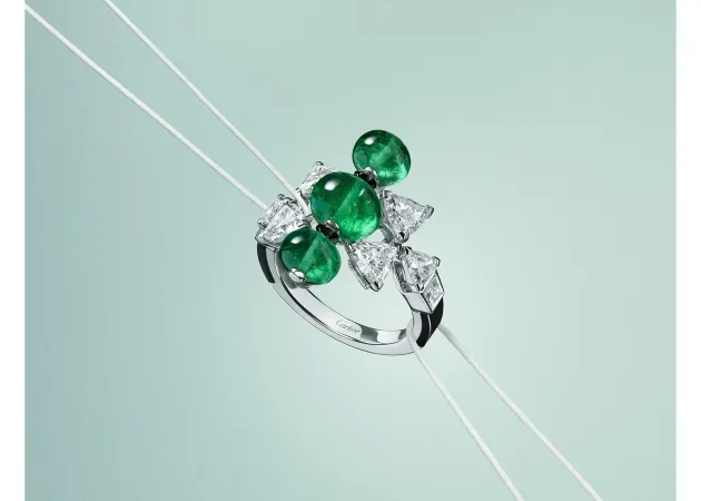 Cartier En Équilibre Summae ring in white gold with cabochon emeralds, troïdia-cut diamonds and onyx on a pale green ground. | Photo: courtesy of Cartier