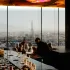 Guests at the bar of Das LOFT in the evening light beneath Pipilotti Rist's illuminated ceiling, with St Stephen's Cathedral rising over Vienna beyond the glass.