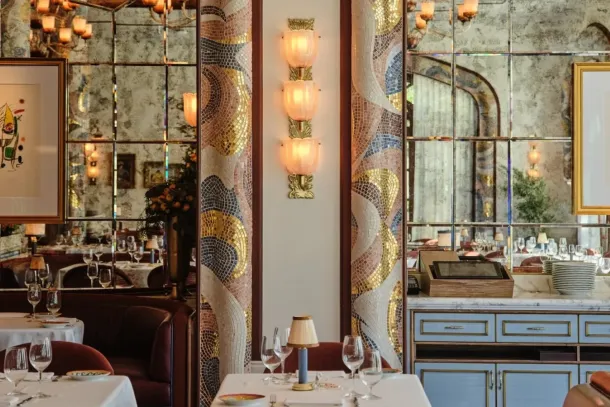The dining room of Carbone Riviera at the Bellagio in Las Vegas, with mosaic arches, a sconce of three ribbed glass cups on a brass stem and tables laid in white. | Credit: Courtesy of Sogni di Cristallo