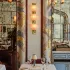 The dining room of Carbone Riviera at the Bellagio in Las Vegas, with mosaic arches, a sconce of three ribbed glass cups on a brass stem and tables laid in white. | Credit: Courtesy of Sogni di Cristallo