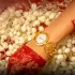 An 18-carat gold Nebula watch by Titan and Tarun Tahiliani on a bride's wrist, resting on jasmine flowers and red lace. Photo: Courtesy of Titan Company