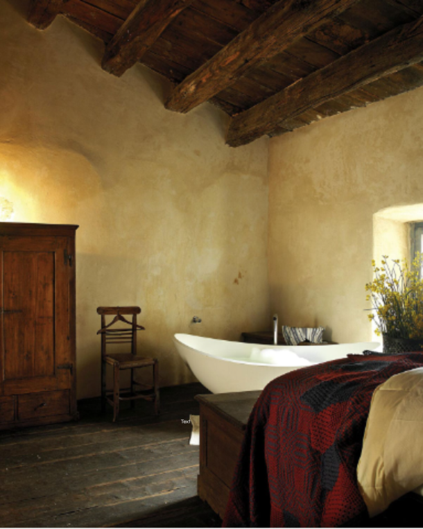 The Albergo Diffuso model preserves the character of historic village buildings rather than renovating them into a standard hospitality product. At Sextantio in Santo Stefano di Sessanio, Abruzzo, original stone walls, hand-hewn ceiling beams and period furniture define the guest experience — the building provides what no designed interior can replicate. Photo: Courtesy Sextantio.